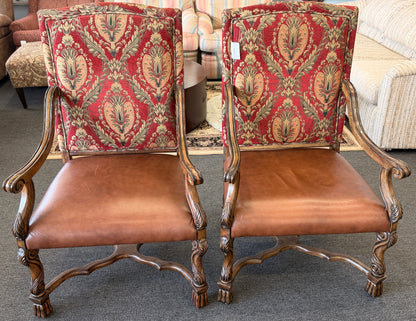 Pair of ornate chairs with red patterned backs and brown leather seats in a room setting.