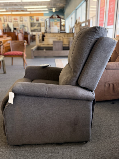 A standard upholstered recliner chair in a solid grayish-brown fabric featuring a structured paneled backrest and padded armrests.