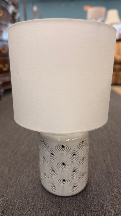 Modern grey geometric diamond cutout ceramic table lamp featuring a textured base and a white drum shade on a gray surface at 2nd Debut Houston consignment showroom