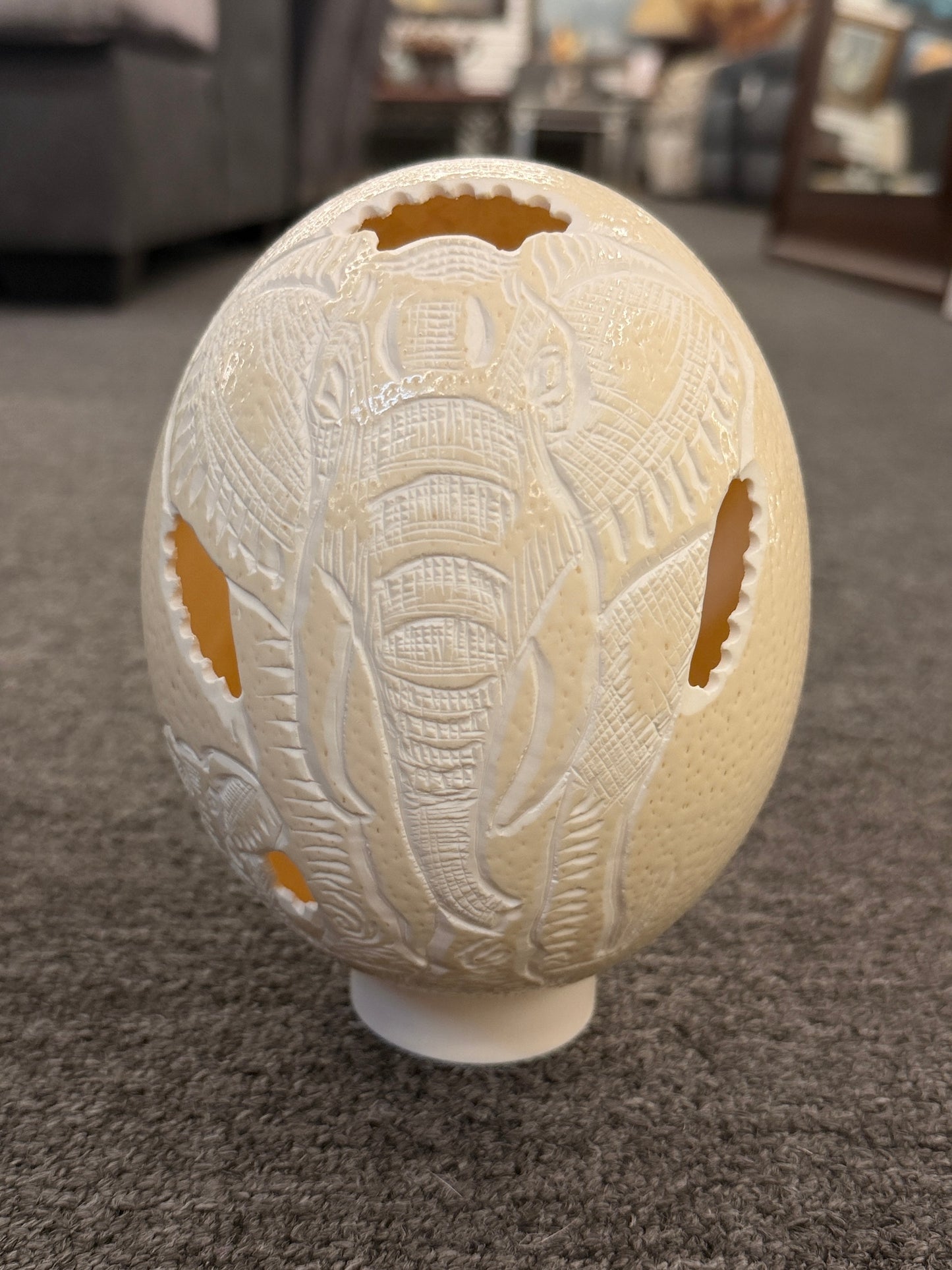 A hollowed genuine ostrich egg shell featuring an intricately carved relief of an African elephant with delicate openwork cutouts.