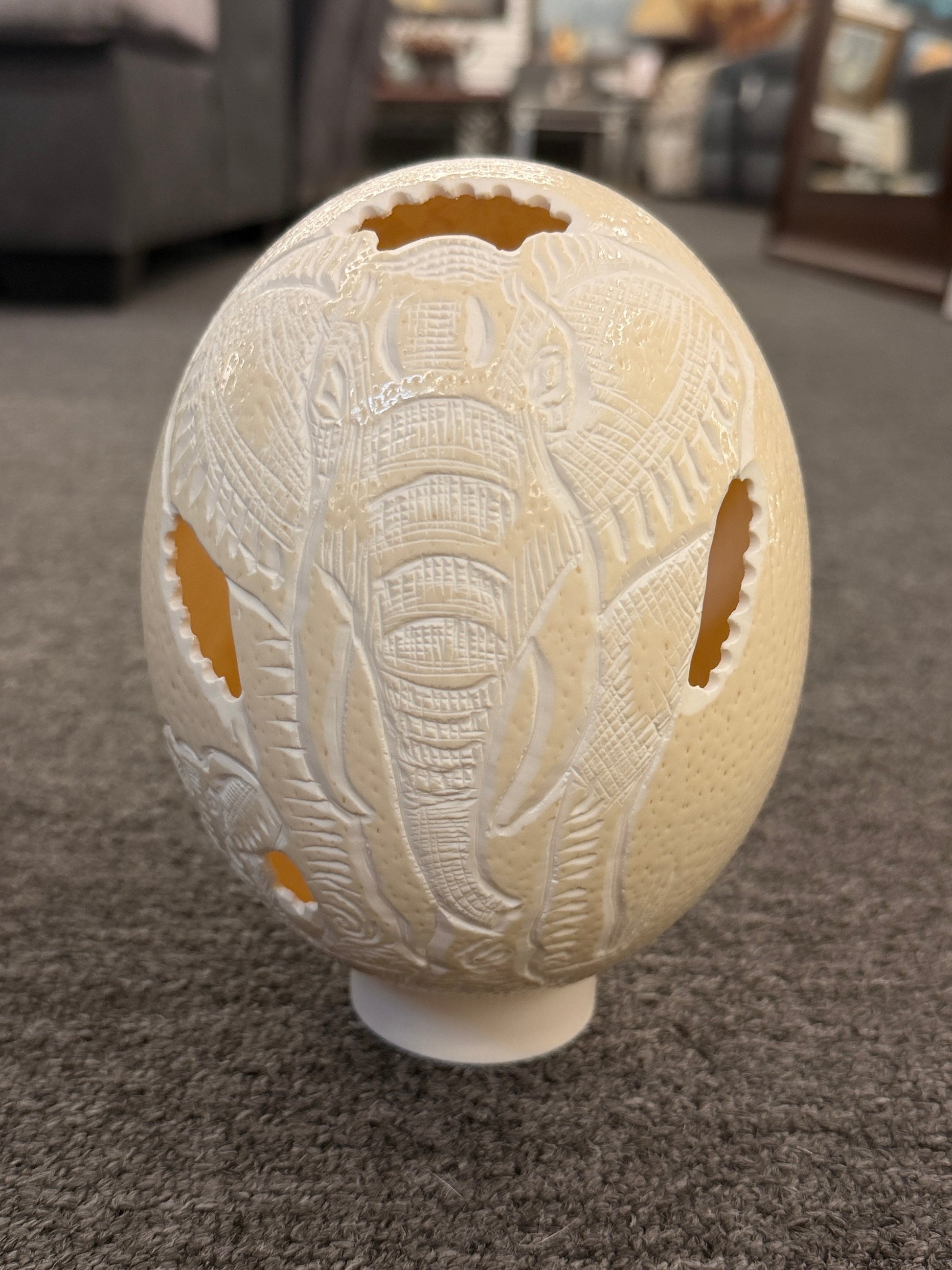A hollowed genuine ostrich egg shell featuring an intricately carved relief of an African elephant with delicate openwork cutouts.