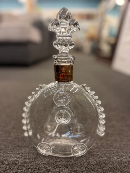 An iconic collector's glass decanter featuring ribbed side flanges, raised medallions, and a Fleur-de-lis crystal stopper in excellent condition.