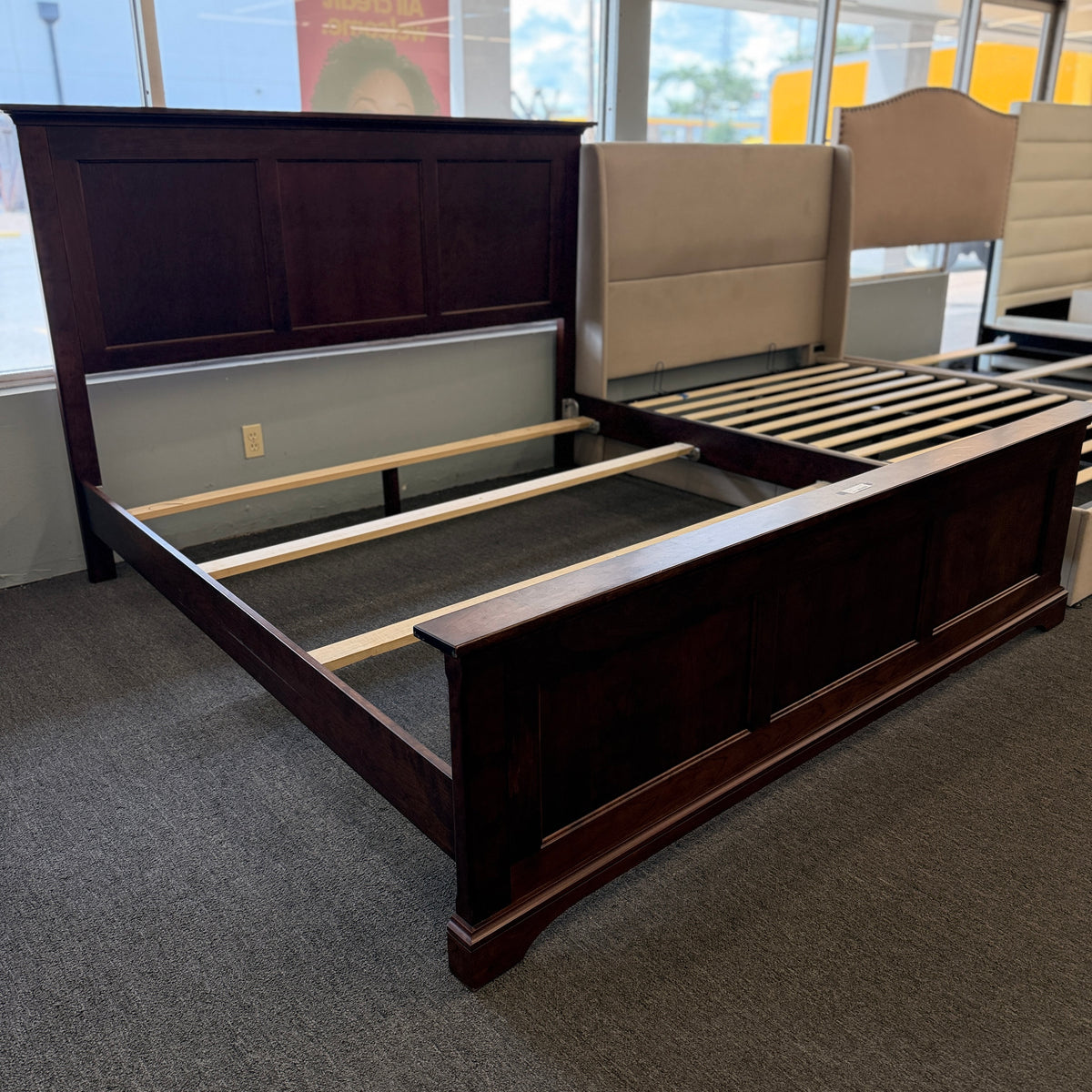 A substantial king-sized wooden bed frame in an espresso finish featuring a high panel headboard, matching footboard, side rails, and supportive slats in excellent condition.