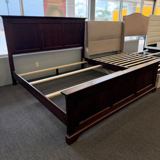 A substantial king-sized wooden bed frame in an espresso finish featuring a high panel headboard, matching footboard, side rails, and supportive slats in excellent condition.