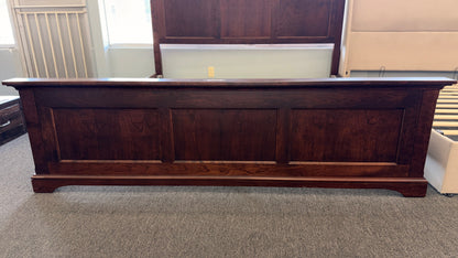 A substantial king-sized wooden bed frame in an espresso finish featuring a high panel headboard, matching footboard, side rails, and supportive slats in excellent condition.