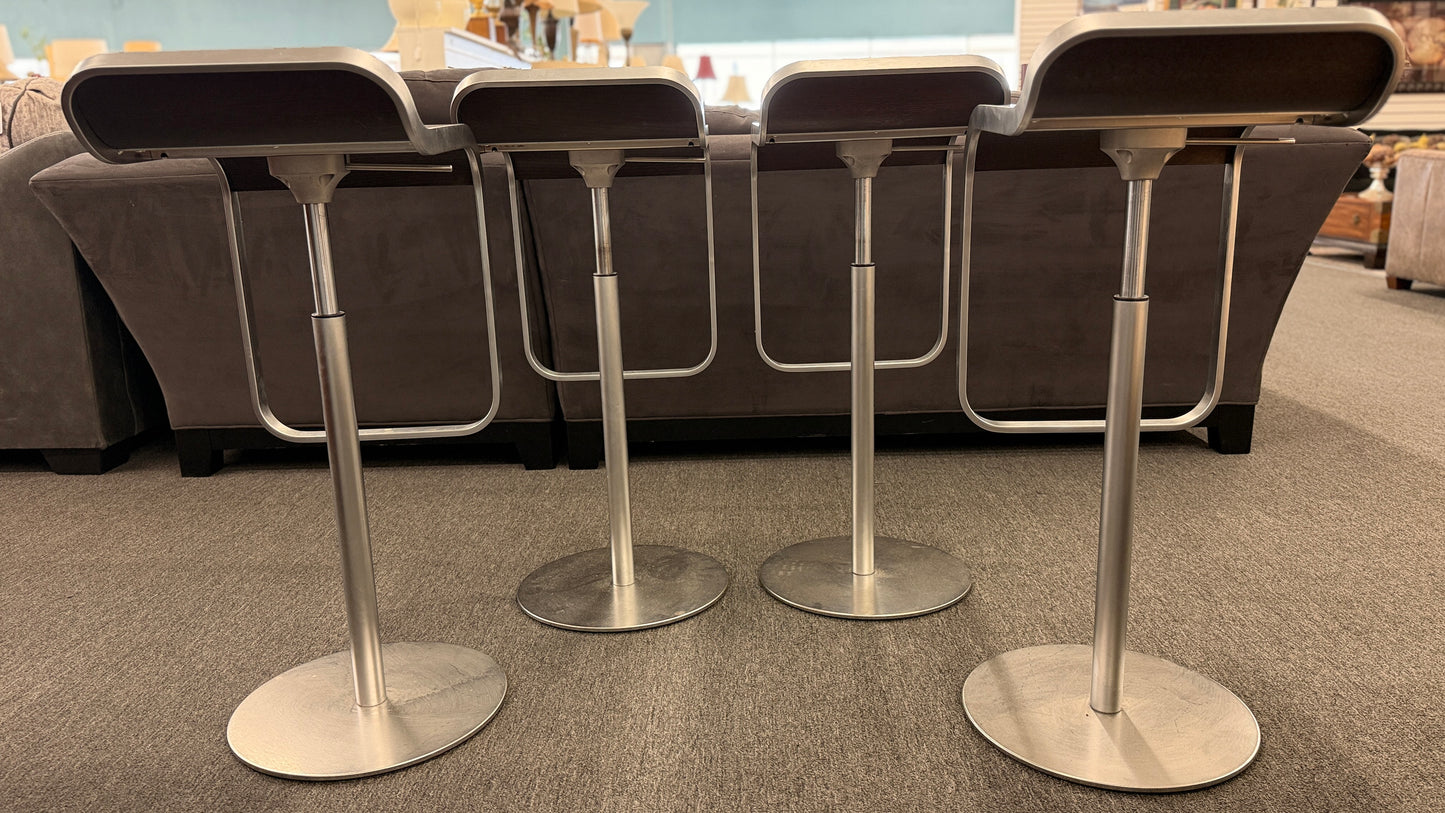 A set of four contemporary Lapalma-style adjustable barstools featuring curved bentwood scoop seats, metal frames, integrated footrests, and heavy disc bases in good condition.