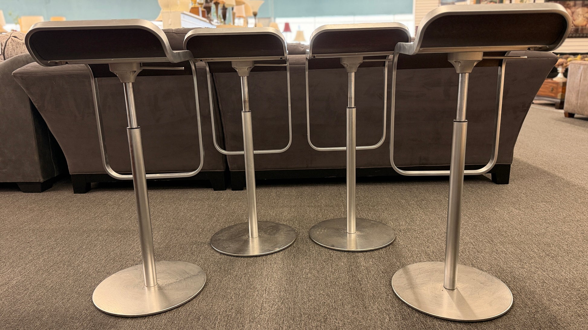 A set of four contemporary Lapalma-style adjustable barstools featuring curved bentwood scoop seats, metal frames, integrated footrests, and heavy disc bases in good condition.