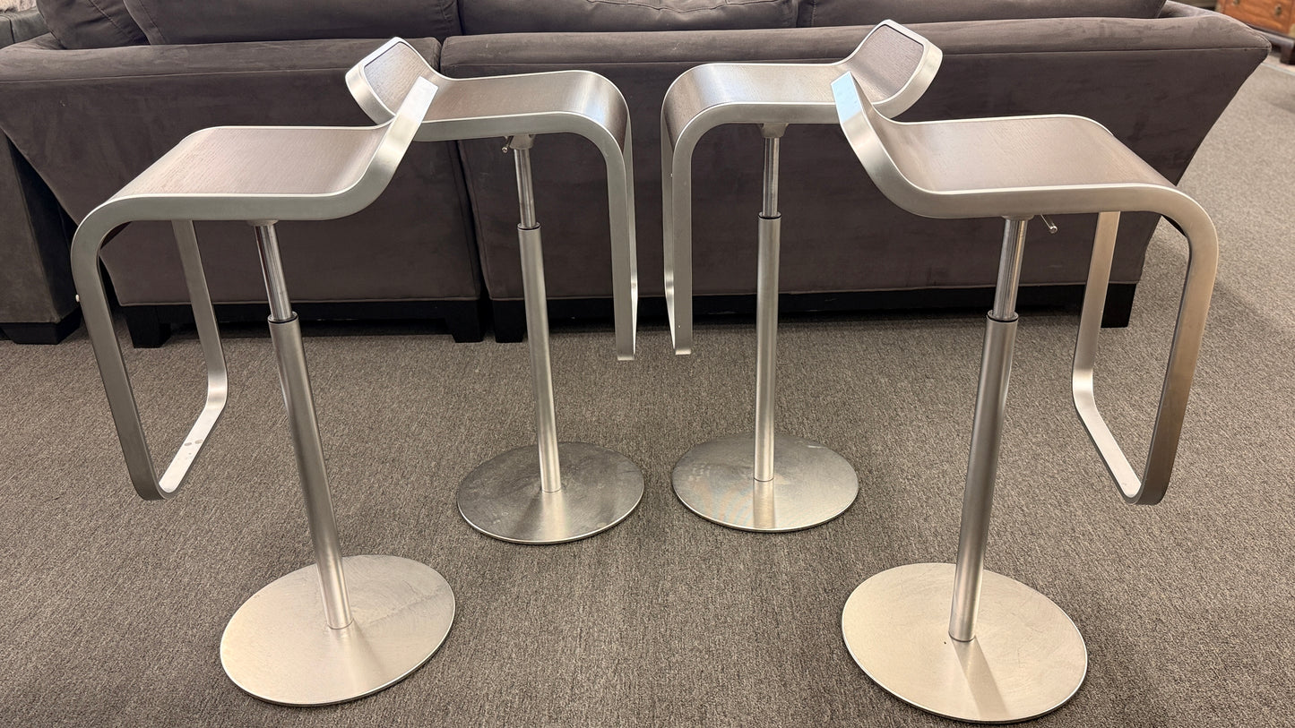 A set of four contemporary Lapalma-style adjustable barstools featuring curved bentwood scoop seats, metal frames, integrated footrests, and heavy disc bases in good condition.