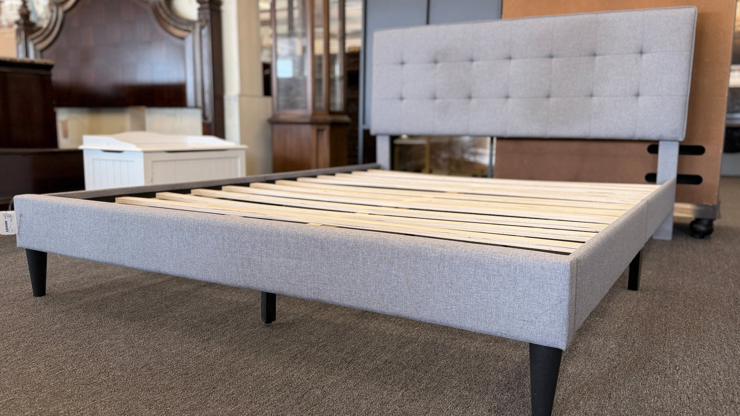 Light gray upholstered queen platform bed featuring a button-tufted headboard, matching upholstered side rails, dark tapered wooden legs, and wooden slat mattress support.