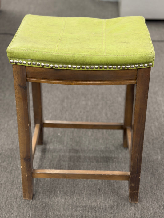 A wooden backless barstool featuring a lime green cushioned leather seat with brass nailhead accents in good condition.