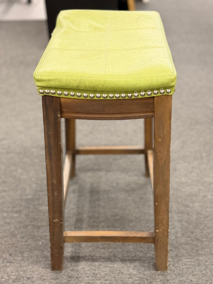 A wooden backless barstool featuring a lime green cushioned leather seat with brass nailhead accents in good condition.