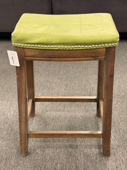 A wooden backless barstool featuring a lime green cushioned leather seat with brass nailhead accents in good condition.