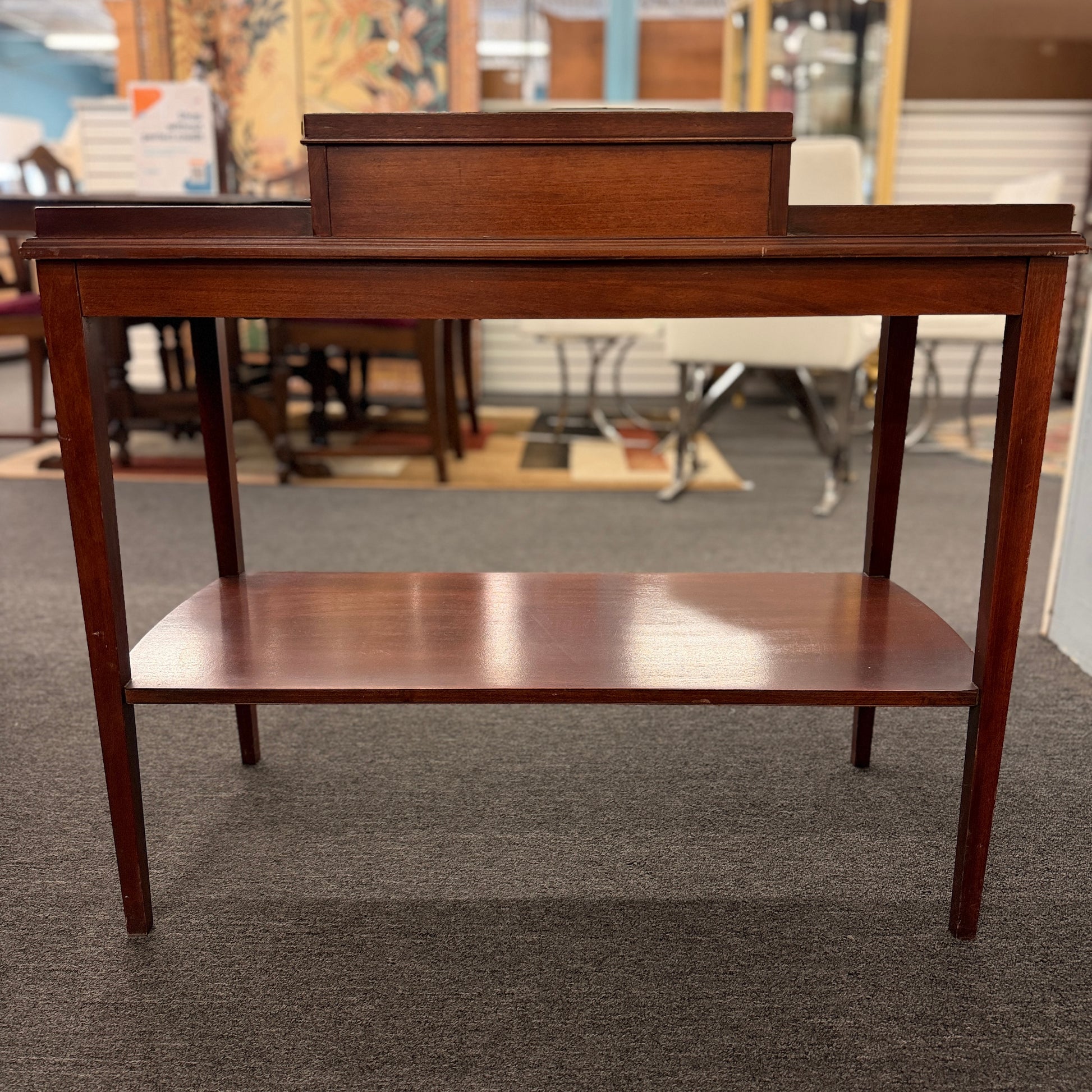 A classic mahogany-finished wooden console entry table featuring a center drawer with oval brass pull, tapered legs, and a lower shelf.