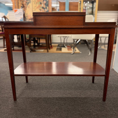 A classic mahogany-finished wooden console entry table featuring a center drawer with oval brass pull, tapered legs, and a lower shelf.