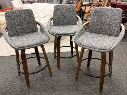 A 3-piece set of mid-century modern barstools featuring textured gray tweed upholstered seats, curved walnut wood armrests, and tapered legs with a black metal footrest ring.