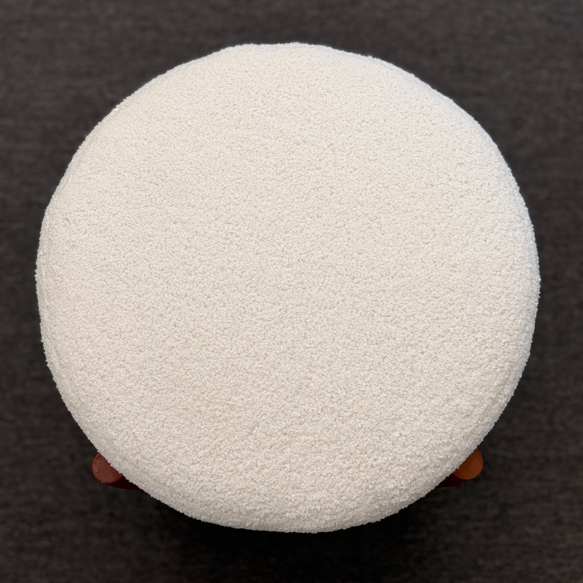 A mid-century modern round accent ottoman featuring a plush, fabric-upholstered cylindrical seat on a structured, four-legged exposed wooden base.