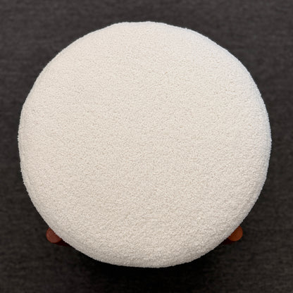 A mid-century modern round accent ottoman featuring a plush, fabric-upholstered cylindrical seat on a structured, four-legged exposed wooden base.