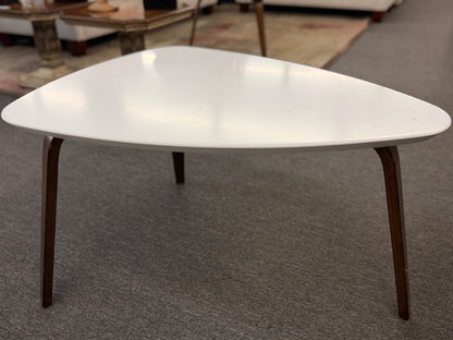 A retro-inspired triangular end table featuring a smooth white guitar-pick-shaped top supported by three splayed, tapered dark wood legs.