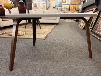 A retro-inspired triangular end table featuring a smooth white guitar-pick-shaped top supported by three splayed, tapered dark wood legs.