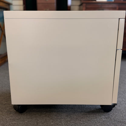 A minimalist two-drawer under-desk pedestal file cabinet featuring curved metal handles, a top lock, and dual casters in good condition.