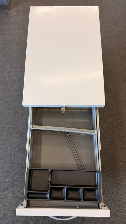 A minimalist two-drawer under-desk pedestal file cabinet featuring curved metal handles, a top lock, and dual casters in good condition.