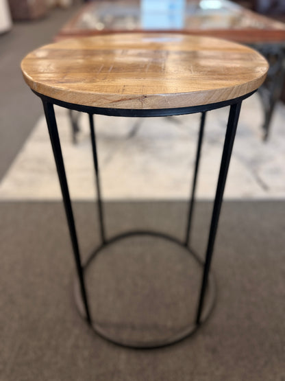 A minimalist round side table featuring a light wood tabletop and a black metal frame in excellent condition.