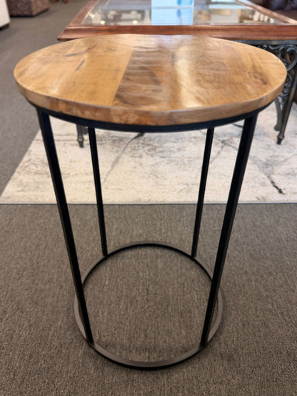 A minimalist round side table featuring a light wood tabletop and a black metal frame in excellent condition.
