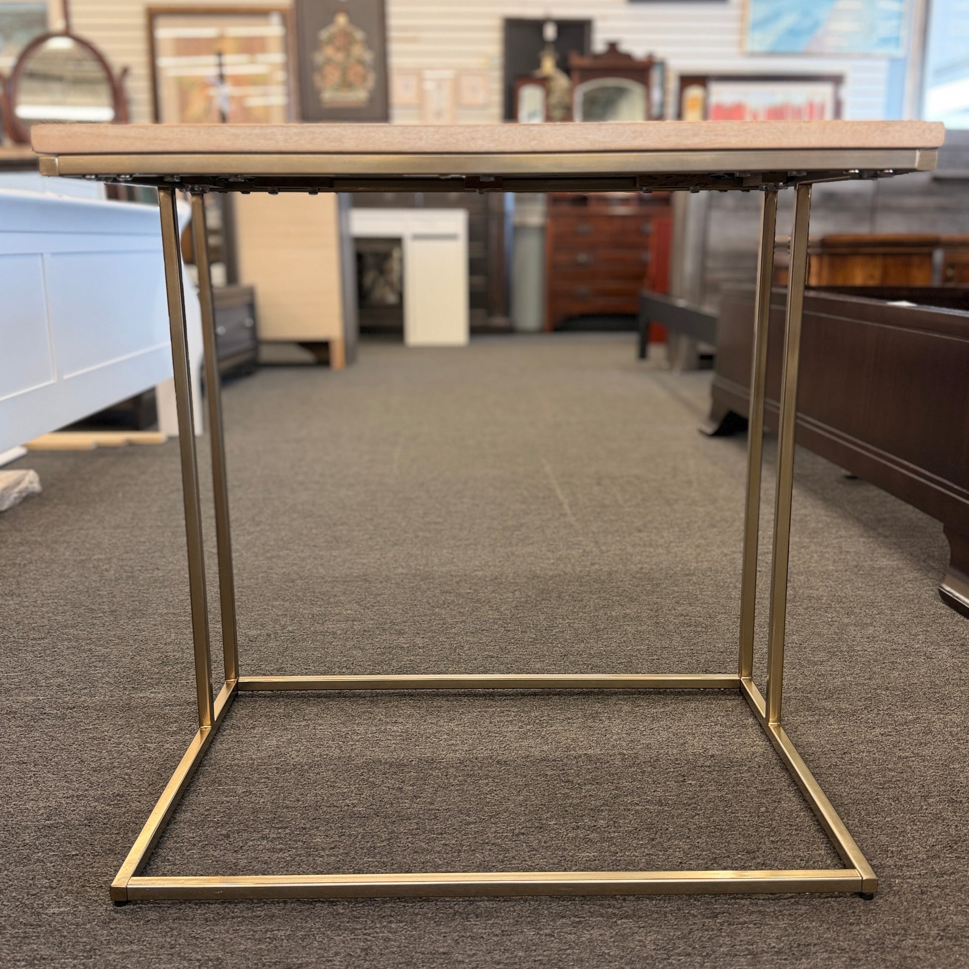 A minimalist C-shaped end table with a wooden tabletop and a slender black metal frame designed to slide over a sofa arm.