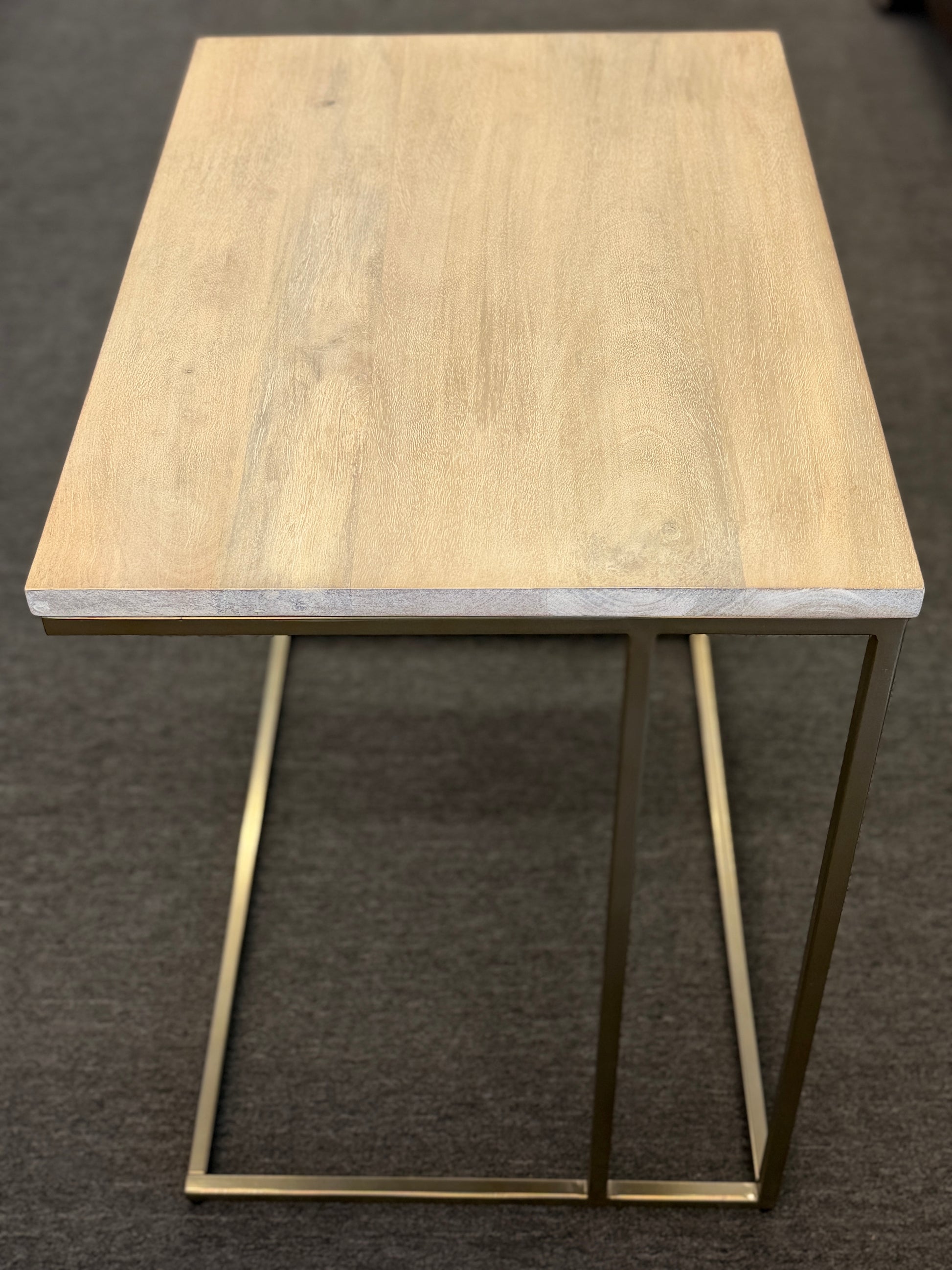 A minimalist C-shaped end table with a wooden tabletop and a slender black metal frame designed to slide over a sofa arm.