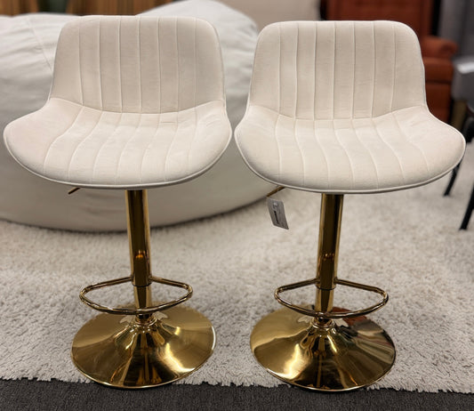 A pair of modern swivel bar stools featuring low-profile upholstered seats with vertical channel tufting on gleaming metallic pedestal bases with footrests.