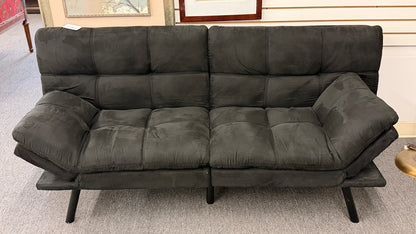 A modern dark charcoal tufted futon sofa featuring adjustable fold-down backrests, pillow-style armrests, and tapered black metal legs.