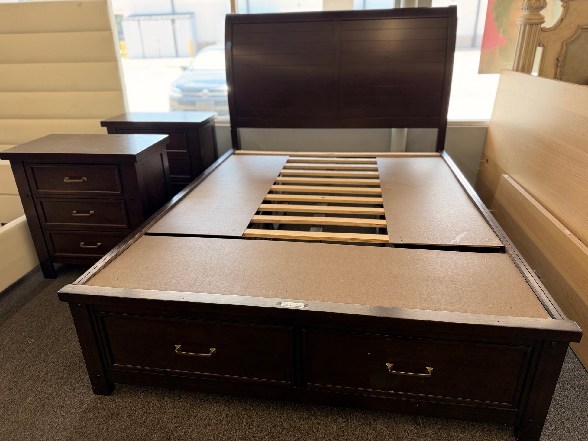 A modern dark-wood queen platform bed frame with a horizontal-paneled headboard, six footboard storage drawers, and matching three-drawer nightstands.