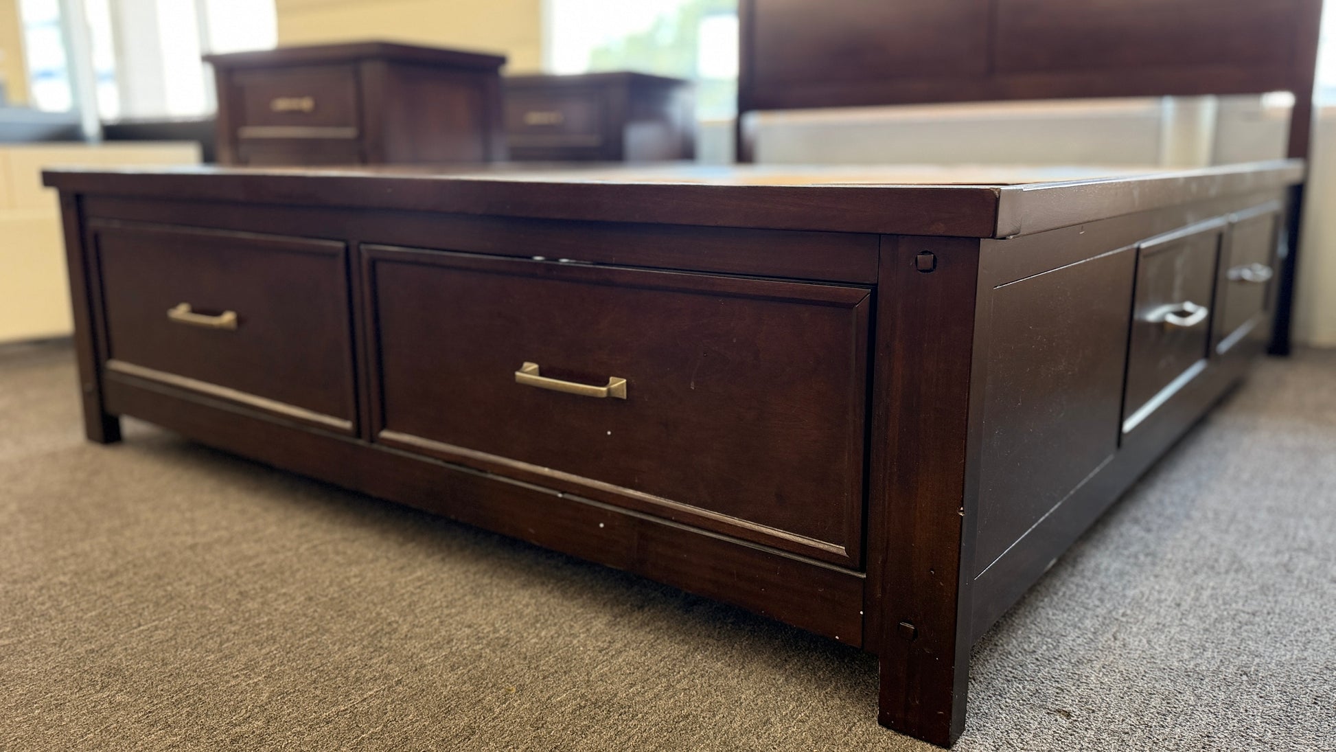 A modern dark-wood queen platform bed frame with a horizontal-paneled headboard, six footboard storage drawers, and matching three-drawer nightstands.