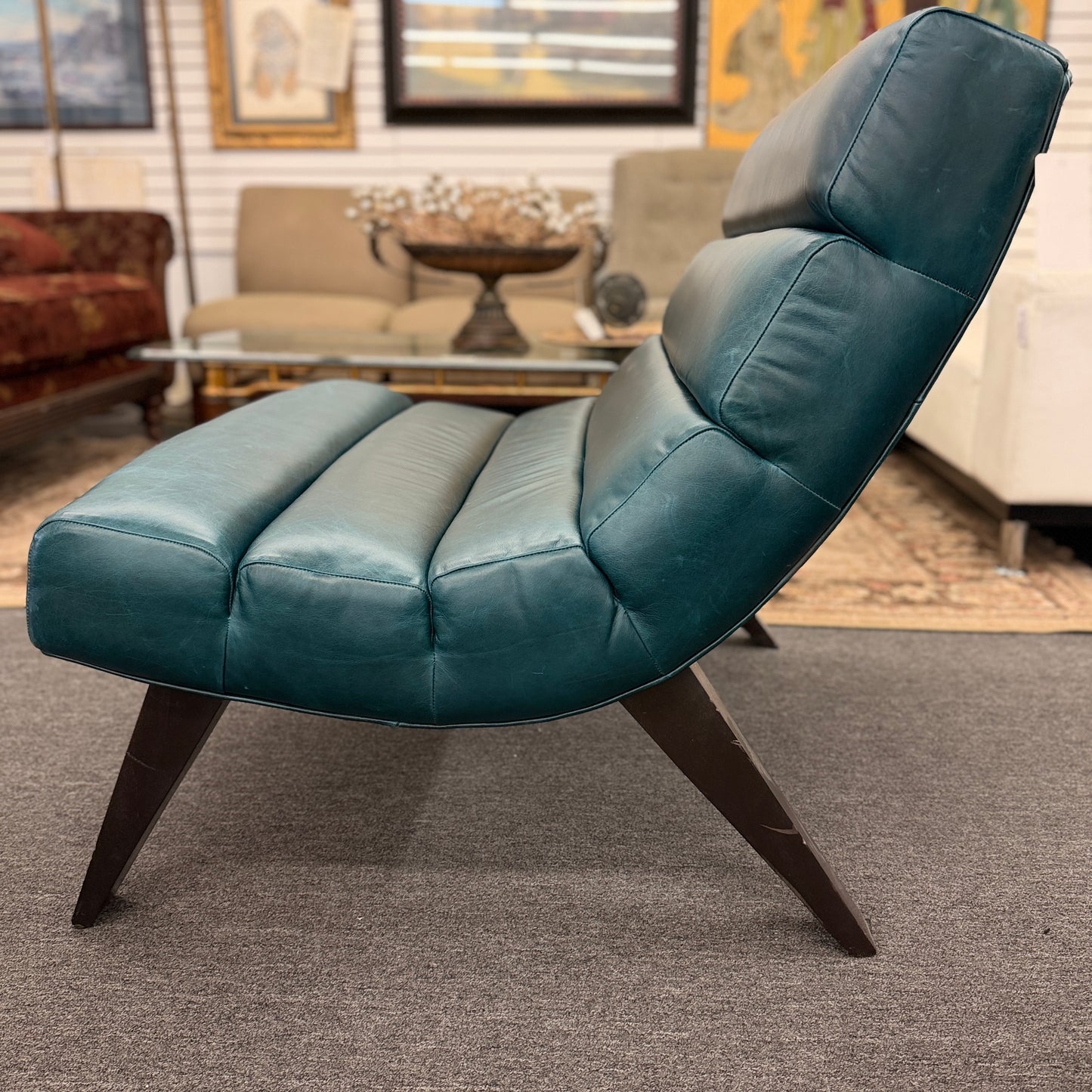 Modern armless accent chair upholstered in distressed teal leather featuring horizontal channel tufting and dark square wooden legs.