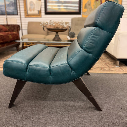 Modern armless accent chair upholstered in distressed teal leather featuring horizontal channel tufting and dark square wooden legs.