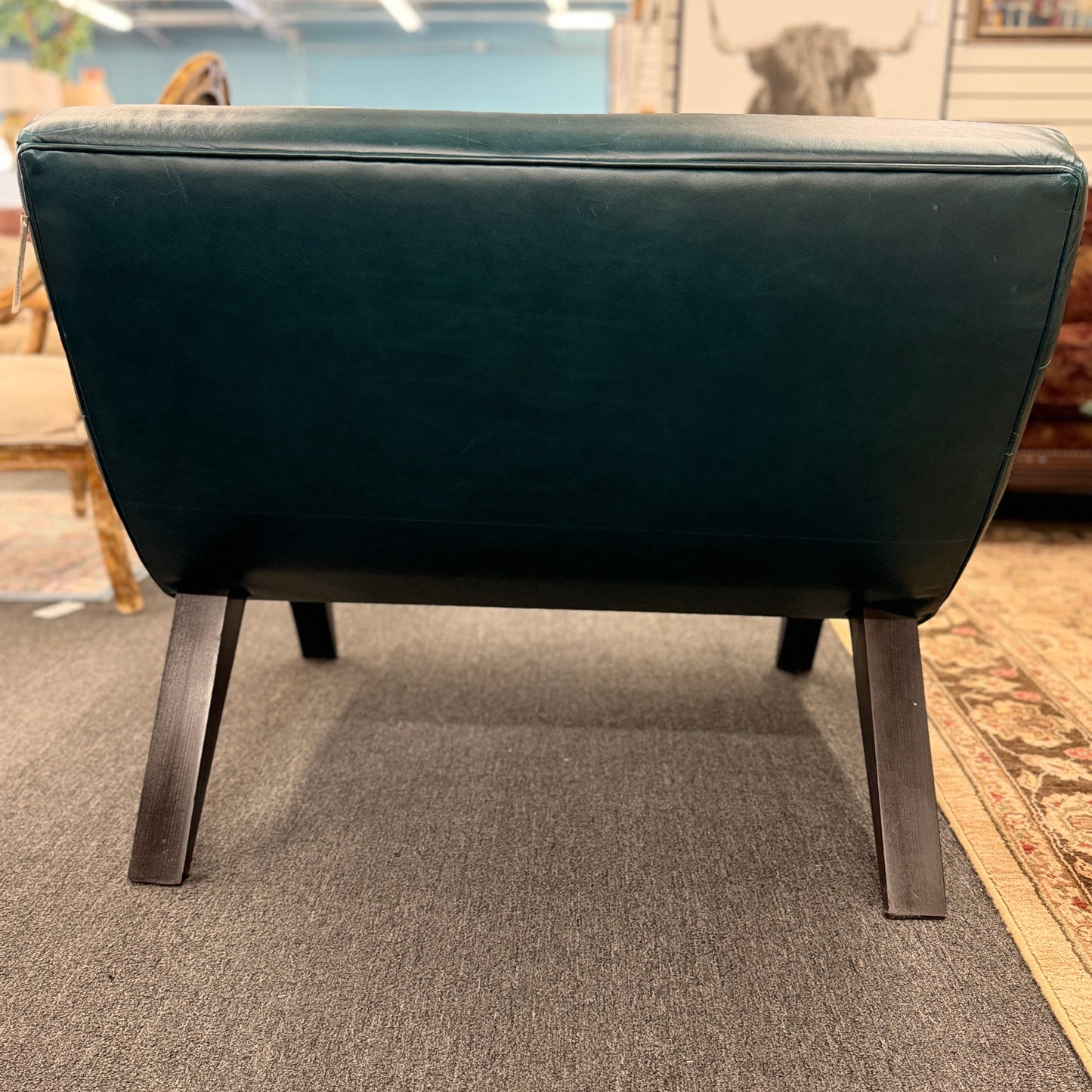 Modern armless accent chair upholstered in distressed teal leather featuring horizontal channel tufting and dark square wooden legs.