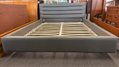 Modern gray upholstered queen platform bed featuring a horizontal channel tufted headboard and wooden slat mattress support without a box spring.