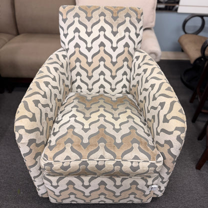 A fully upholstered swivel armchair featuring a wavy geometric chevron pattern in shades of grey, beige, and tan.