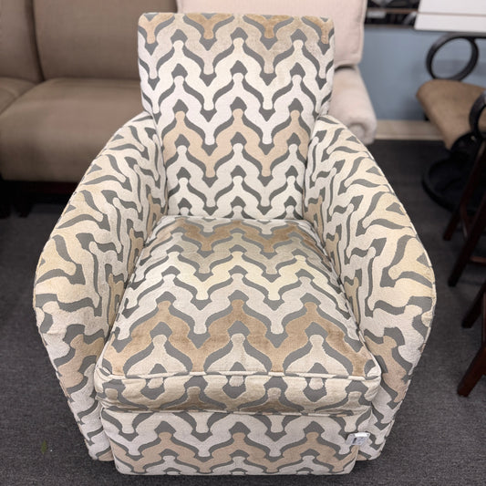 A fully upholstered swivel armchair featuring a wavy geometric chevron pattern in shades of grey, beige, and tan.
