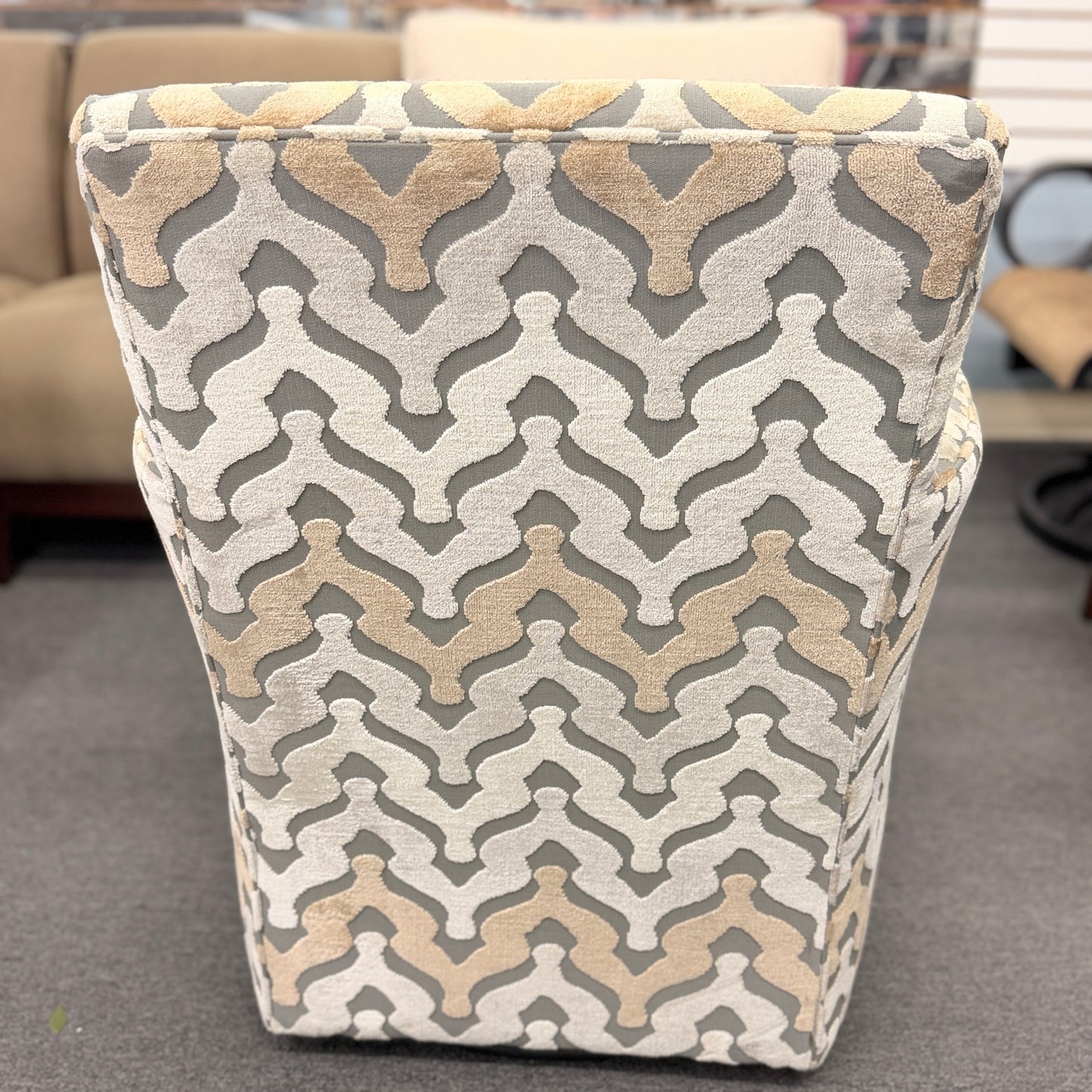 A fully upholstered swivel armchair featuring a wavy geometric chevron pattern in shades of grey, beige, and tan.