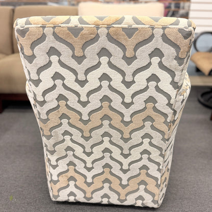 A fully upholstered swivel armchair featuring a wavy geometric chevron pattern in shades of grey, beige, and tan.