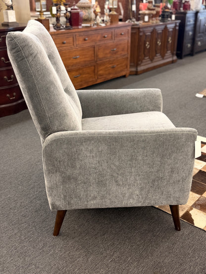 A sleek push-back recliner chair upholstered in heather-gray textured fabric featuring track arms, subtle vertical tufting, and tapered dark wood legs in excellent condition.