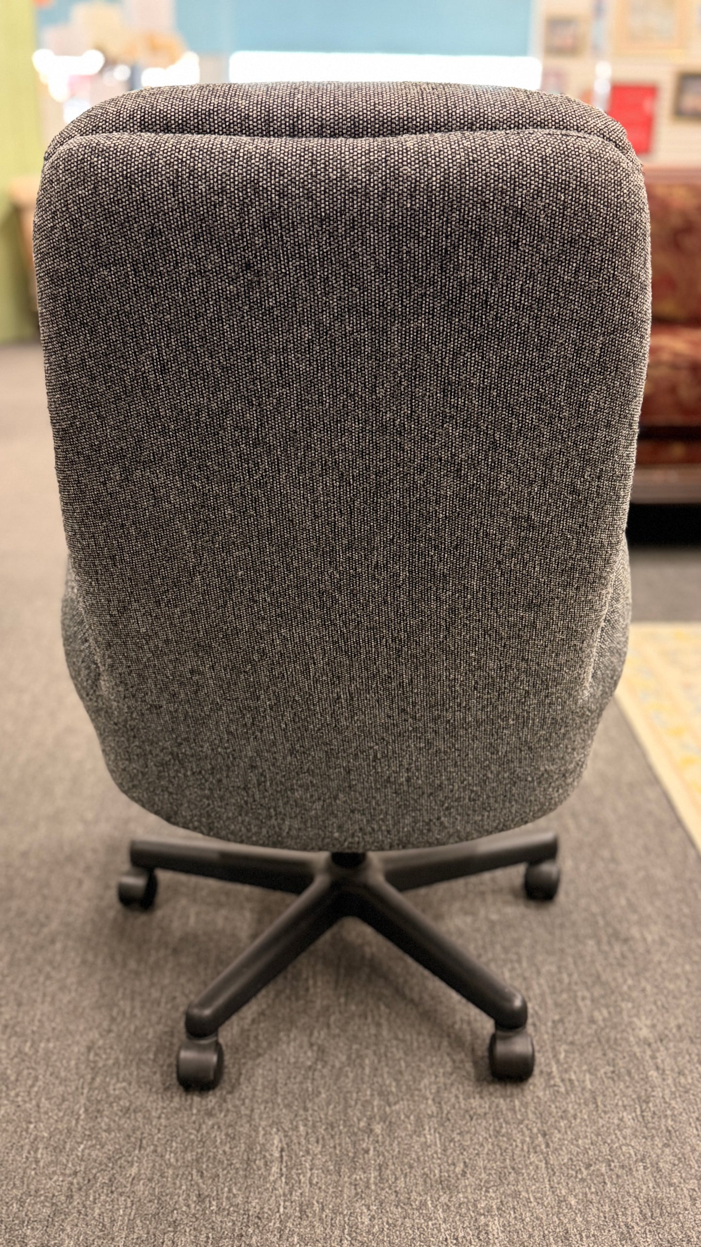 A modern minimalist high-back swivel office chair upholstered in textured grey fabric on a dark five-point wheeled base.
