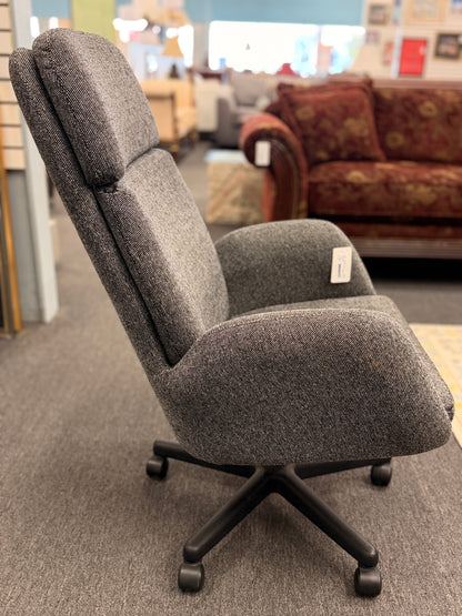 A modern minimalist high-back swivel office chair upholstered in textured grey fabric on a dark five-point wheeled base.