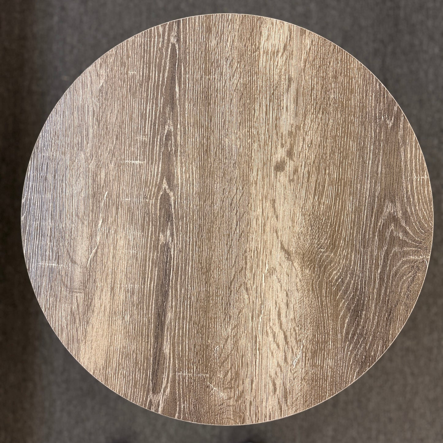 A round two-tiered end table featuring a distressed faux wood-grain finish on both circular shelves with a minimalist black iron frame.