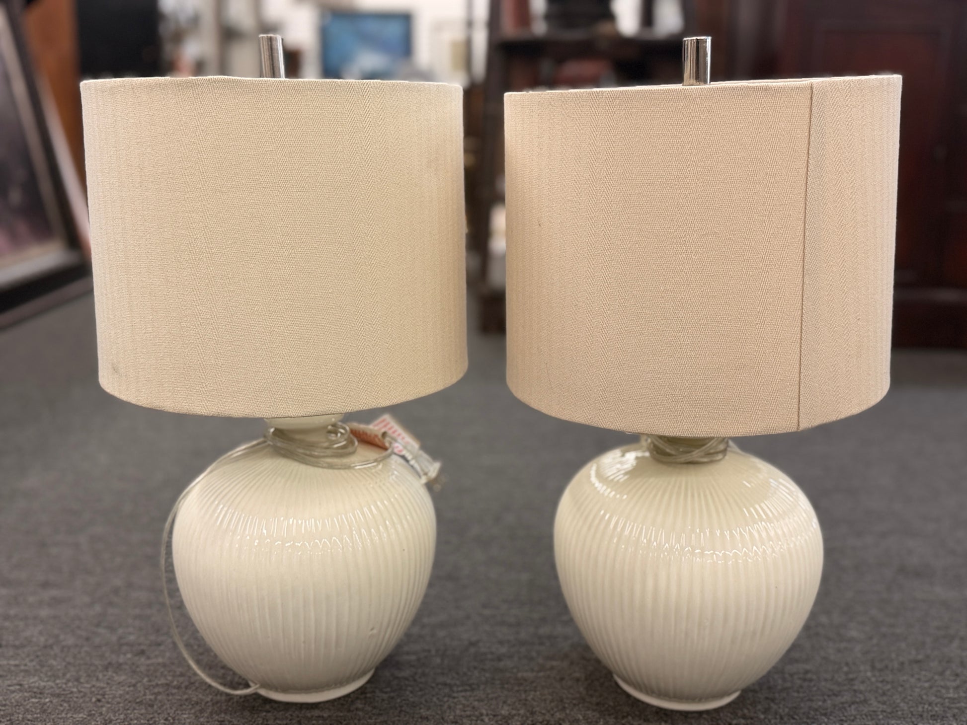 A pair of matching table lamps featuring textured spherical ceramic bases and neutral-colored fabric drum shades.