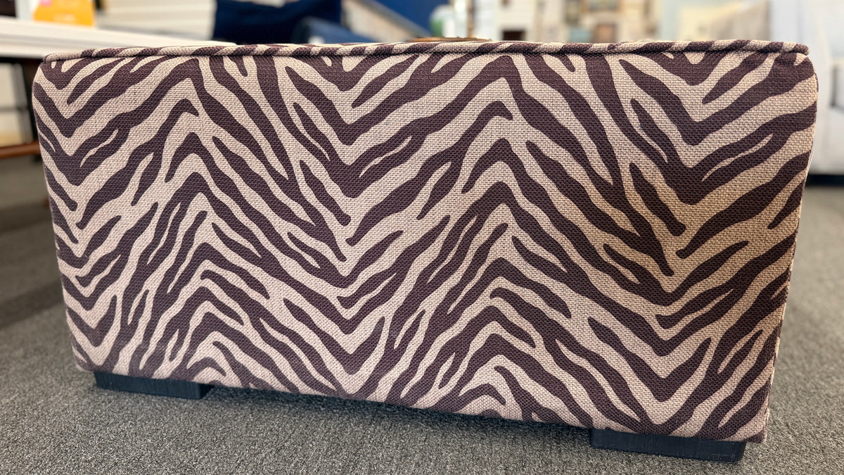 A modern square cube ottoman upholstered in a textured brown and beige zebra-stripe woven fabric in good condition.