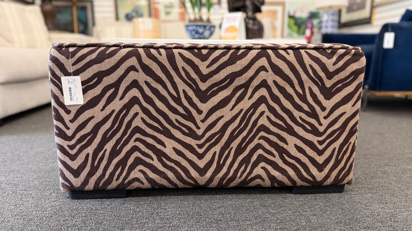 A modern square cube ottoman upholstered in a textured brown and beige zebra-stripe woven fabric in good condition.