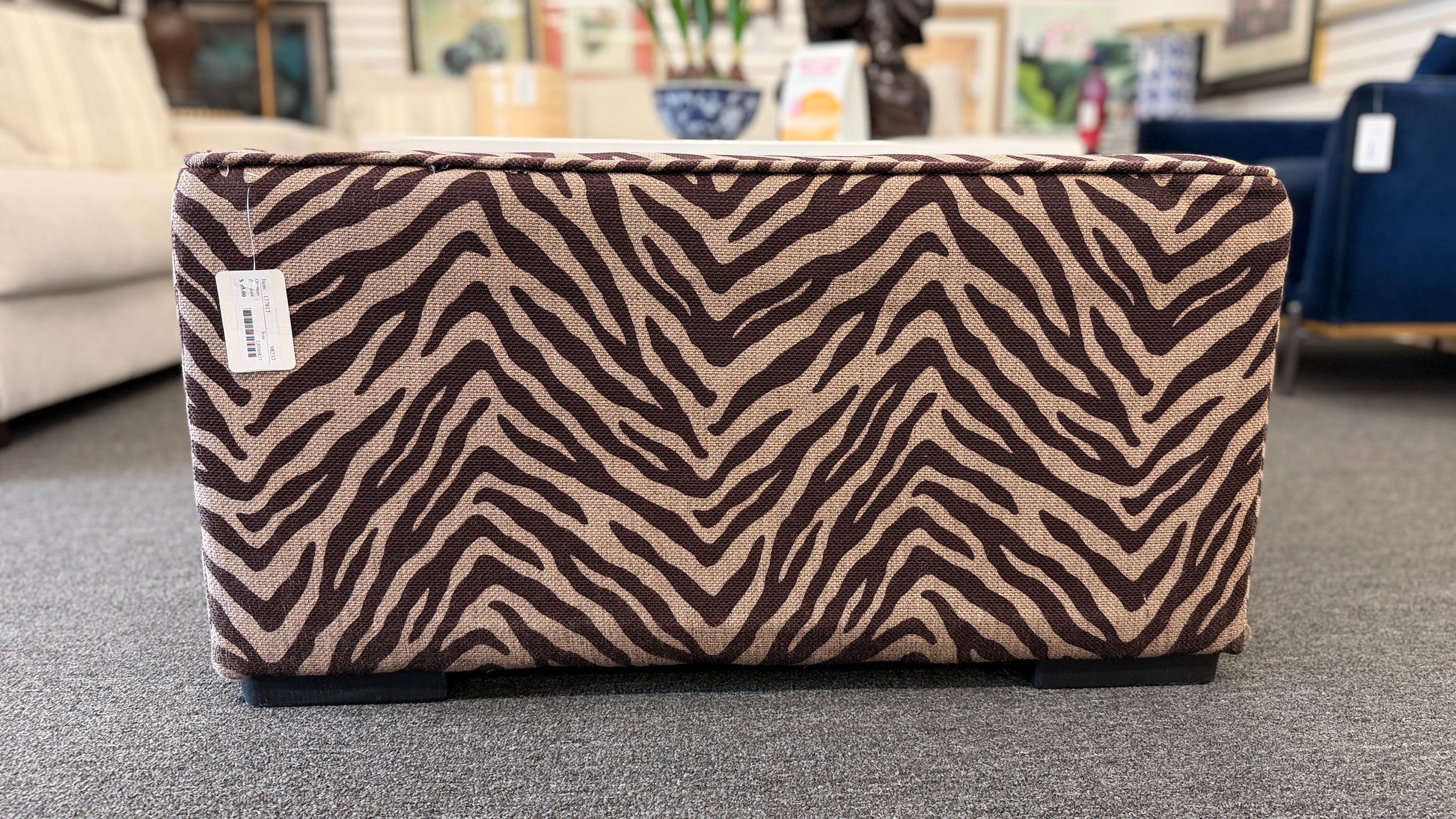 A modern square cube ottoman upholstered in a textured brown and beige zebra-stripe woven fabric in good condition.