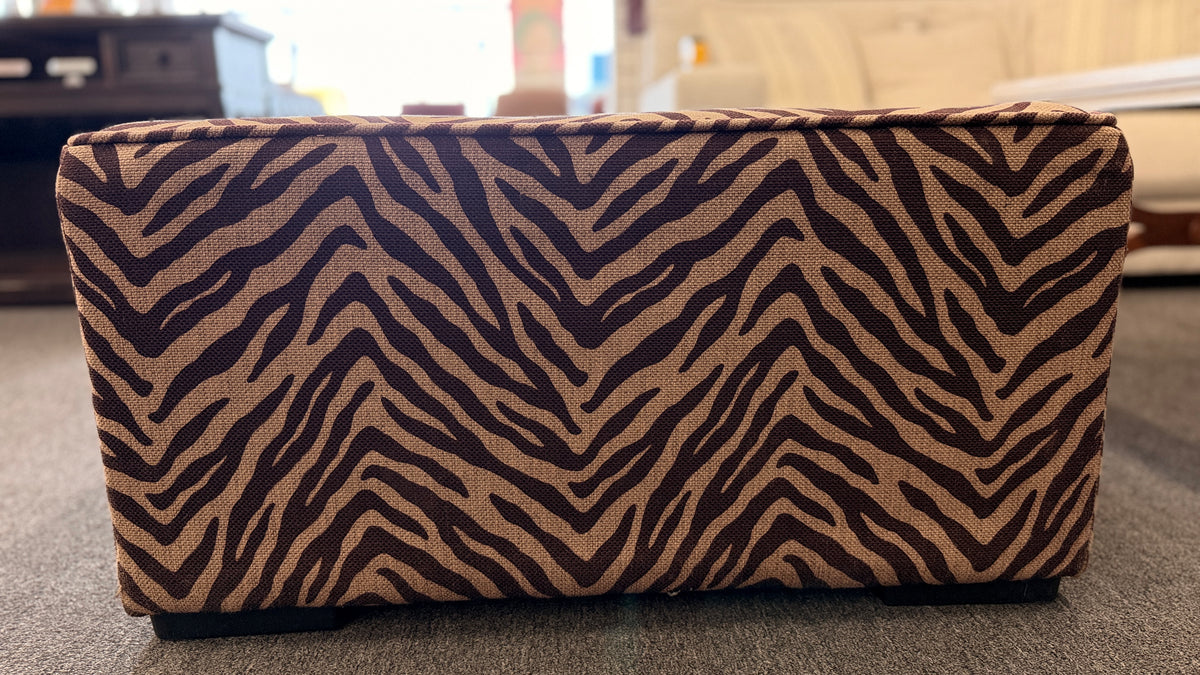 A modern square cube ottoman upholstered in a textured brown and beige zebra-stripe woven fabric in good condition.